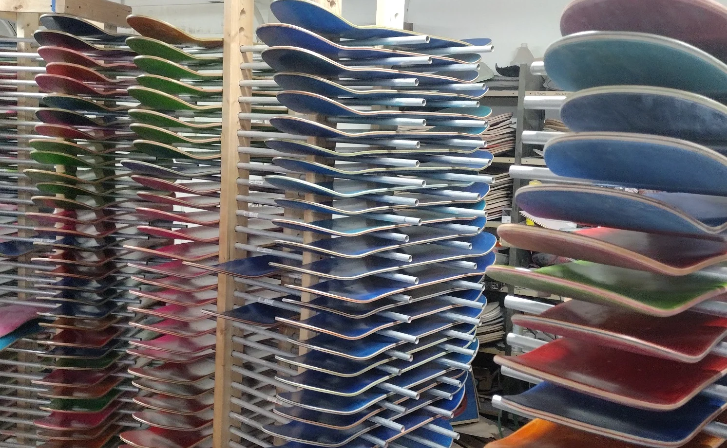 Skateboard decks on production racks inside Empire Skateboard Manufacturing