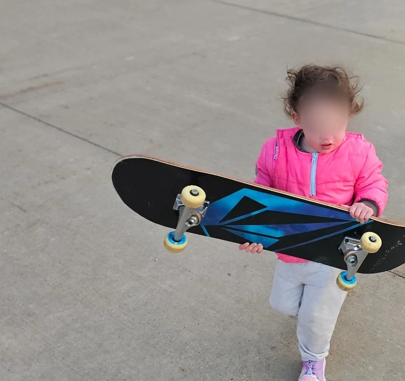 Young student holding a completed skateboard with face blurred for privacy